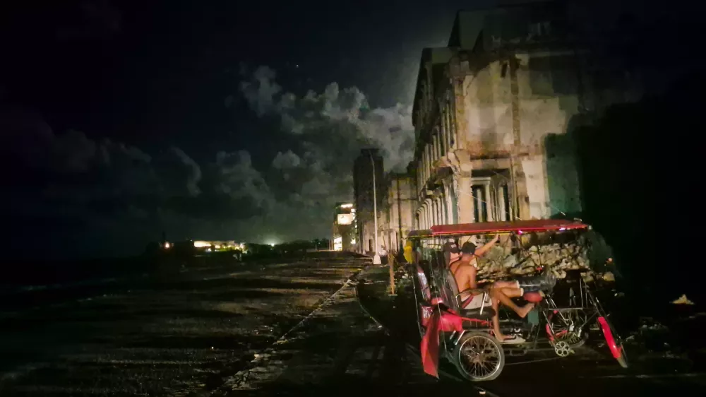 20 October 2024, Cuba, Havana: Two men sit in a bicycle cab during a blackout in Havana, following the failure of a major power plant. Hurricane Oscar on Sunday evening made landfall in Cuba, where much of the population has been without power for over 50 hours due to the collapse of the country's outdated power grid. Photo: Nick Kaiser/dpa