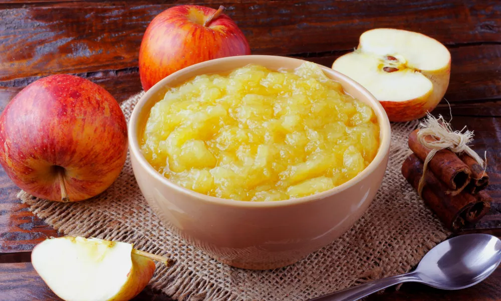 homemade apple sauce or apple puree in ceramic bowl over rustic wooden table. top view / Foto: Gilnature