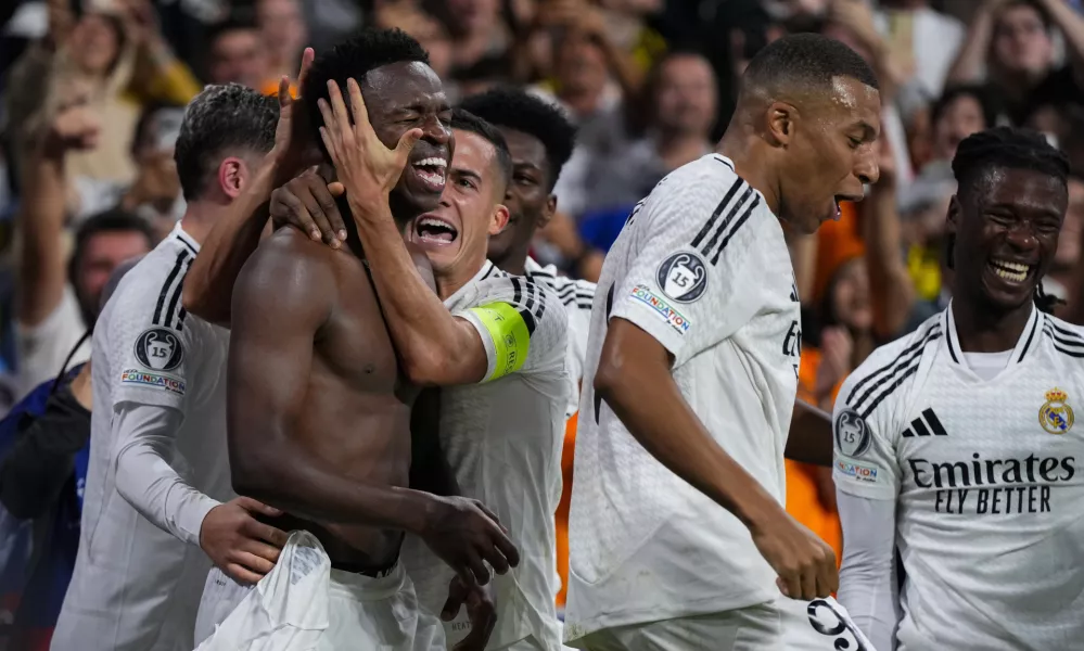 Real Madrid's Vinicius Junior, left, celebrates with teammates after scoring his side's fourth goal during the Champions League opening phase soccer match between Real Madrid and Borussia Dortmund at the Santiago Bernabeu stadium in Madrid, Tuesday, Oct. 22, 2024. Real Madrid won 5-2. (AP Photo/Manu Fernandez)