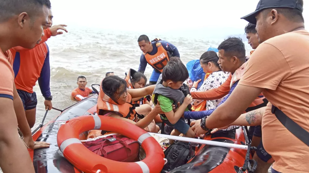 In this photo provided by the Philippine Coast Guard, residents alight a rubber boat after being ferried to safer grounds in Batangas province, Philippines on Friday, Oct. 25, 2024. (Philippine Coast Guard via AP)