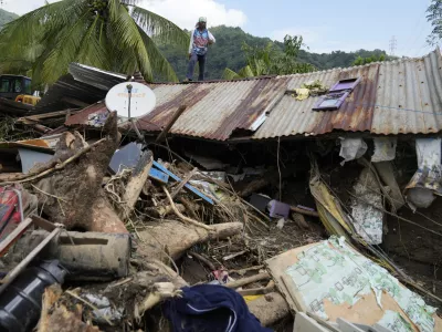 Marcelino Aringo stands on top of a damaged house after a landslide triggered by Tropical Storm Trami recently struck Talisay, Batangas province, Philippines, Saturday, Oct. 26, 2024. (AP Photo/Aaron Favila)