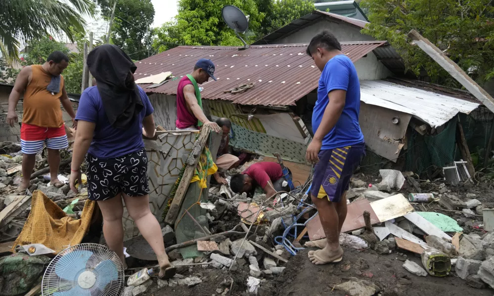 Residents try to recover personal belongings from their damaged home after a landslide triggered by Tropical Storm Trami recently struck Talisay, Batangas province, Philippines, Saturday, Oct. 26, 2024. (AP Photo/Aaron Favila)