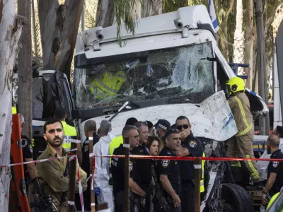 Israeli police and rescue services inspect the site where a truck driver rammed into a bus stop near an army base, wounding dozens of people, according to Israel's Magen David Adom rescue service in Ramat Hasharon, Israel, Sunday, Oct. 27, 2024. (AP Photo/Oded Balilty)