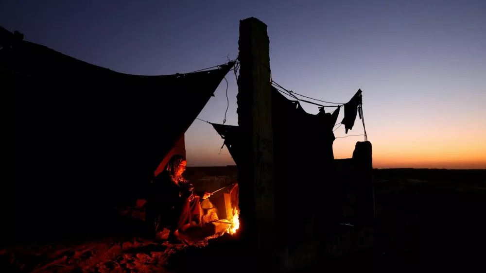 Displaced Palestinian light a fire next to their tent as they live at a cemetery, amid the Israel-Hamas conflict, in Khan Younis, in the southern Gaza Strip, October 27, 2024. REUTERS/Mohammed Salem