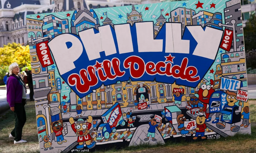 A woman stands next to a mural, part of the "To the Polls" temporary exhibition ahead of election day, at John F. Kennedy Plaza, known as Love Park, in Philadelphia, Pennsylvania, U.S., October 25, 2024. REUTERS/Hannah McKay