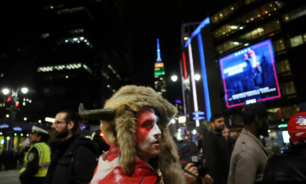 A person dressed as the "QAnon Shaman" looks on as pedestrians walk past outside of Madison Square Garden during a rally for Republican presidential nominee and former U.S. President Donald Trump in New York City, U.S., October 27, 2024. REUTERS/Leah Millis