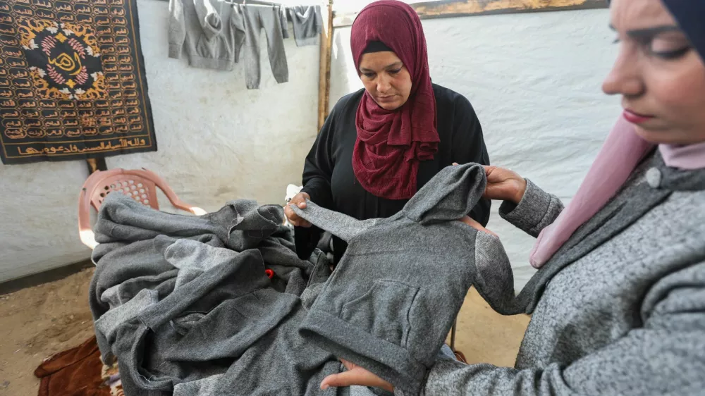 Palestinian Nidaa Attia (R) and another woman display winter clothes they sewed for displaced people from from blankets, amid clothing shortages, at a tent in Khan Younis in the southern Gaza Strip, October 26, 2024. REUTERS/Ramadan Abed