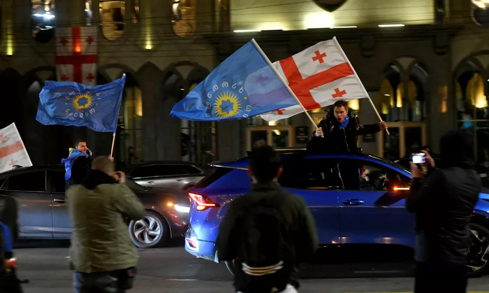 FILE PHOTO: Supporters of the Georgian Dream party wave Georgian flags and the party's flags from cars after the announcement of exit poll results in parliamentary elections, in Tbilisi, Georgia October 26, 2024. REUTERS/Zurab Javakhadze/File Photo