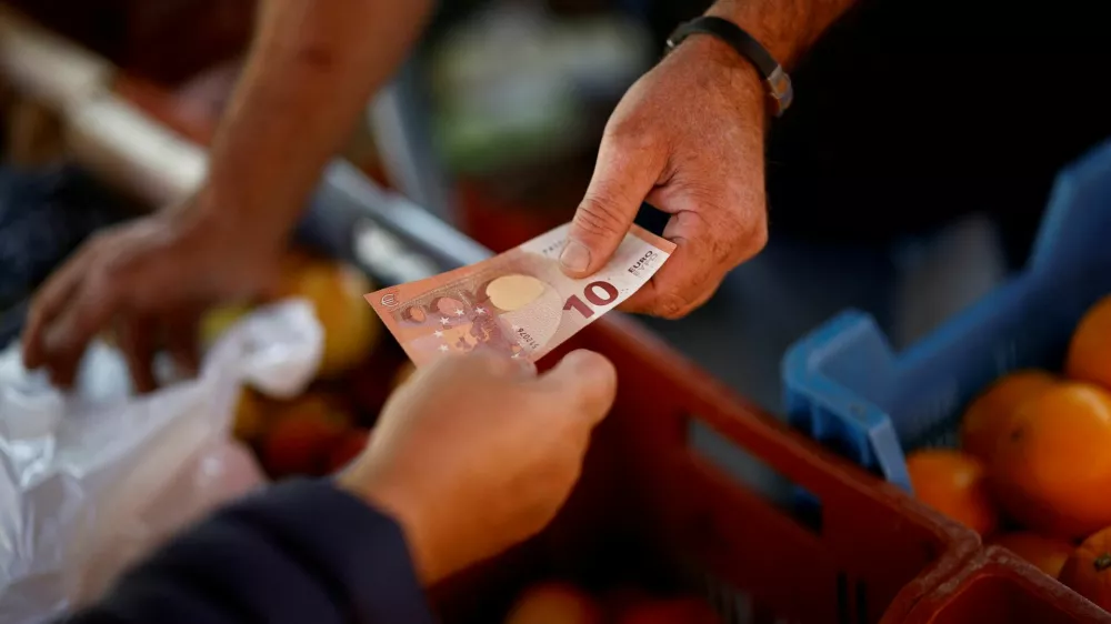 FILE PHOTO: A shopper pays with a ten Euro bank note at a local market in Nantes, France, September 17, 2024. REUTERS/Stephane Mahe/File Photo