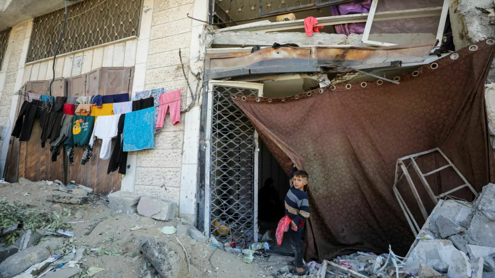 A displaced Palestinian boy stands outside a damaged store where he shelters with his family who fled northern Gaza due to an Israeli military operation, shelter in a school in Gaza City, October 28, 2024. REUTERS/Dawoud Abu Alkas