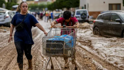 Two people push a cart loaded with belongings in Valencia, Spain, Thursday, Oct. 31, 2024. (AP Photo/Manu Fernandez)