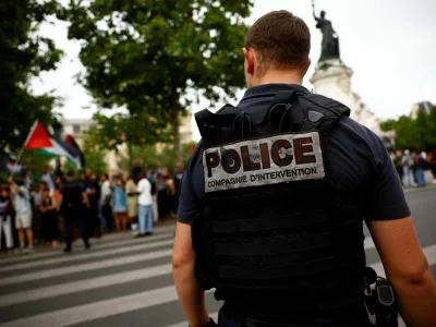 French police stand in position as protesters hold Palestinian flags during a demonstration by social and environmental activists at Place de la Republique, denouncing the Olympics for its environmental record and for driving out homeless people from Paris, on the eve of the opening ceremony of the Paris 2024 Olympic Games, in Paris, France, July 25, 2024. REUTERS/Sarah Meyssonnier