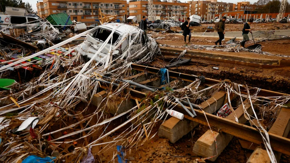 People walk past rail road tracks, damaged cars and debris after heavy rains in Alfafar, in Valencia, Spain, November 1, 2024. REUTERS/Susana Vera    TPX IMAGES OF THE DAY