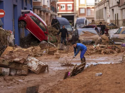 A man cleans the street from mud in an area affected by floods in Valencia, Spain, Saturday, Nov. 2, 2024. (AP Photo/Manu Fernandez)