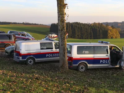 Police vehicles and a police helicopter stand near a field in the village Fraunschalg near Altenfelden, Austria, Monday, Oct. 28, 2024, after people were fatally shot in the area. (AP Photo/laumat/Matthias Lauber)