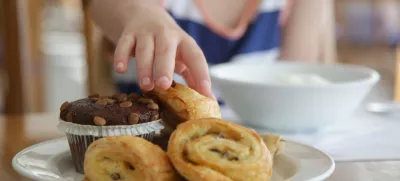 Close up of child's hand taking pastry from plate / Foto: Triocean