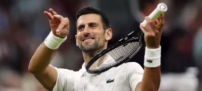 Novak Djokovic of Serbia pretends to play a violin after defeating Holger Rune of Denmark in their fourth round match at the Wimbledon tennis championships in London, Monday, July 8, 2024. (Mike Egerton/PA via AP)