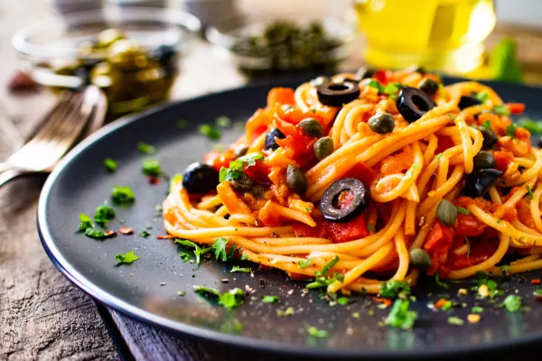 Pasta puttanesca with tomato sauce, anchovies, chilli, capers and olives on wooden table / Foto: Gbh007