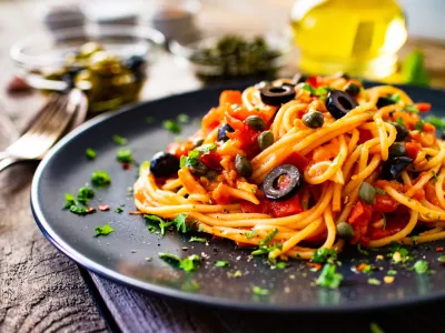 Pasta puttanesca with tomato sauce, anchovies, chilli, capers and olives on wooden table / Foto: Gbh007