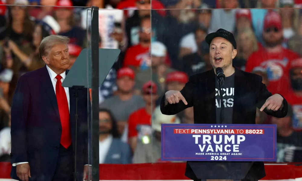 FILE PHOTO: Tesla CEO and X owner Elon Musk speaks as Republican presidential nominee and former U.S. president Donald Trump looks on during a rally at the site of the July assassination attempt against Trump, in Butler, Pennsylvania, U.S., October 5, 2024. REUTERS/Carlos Barria/File Photo