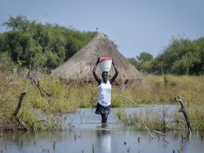 FILE - A woman carries a bucket on her head as she wades through floodwaters in the village of Wang Chot, Old Fangak county, Jonglei state, South Sudan, on Nov. 26, 2020. (AP Photo/Maura Ajak, File)