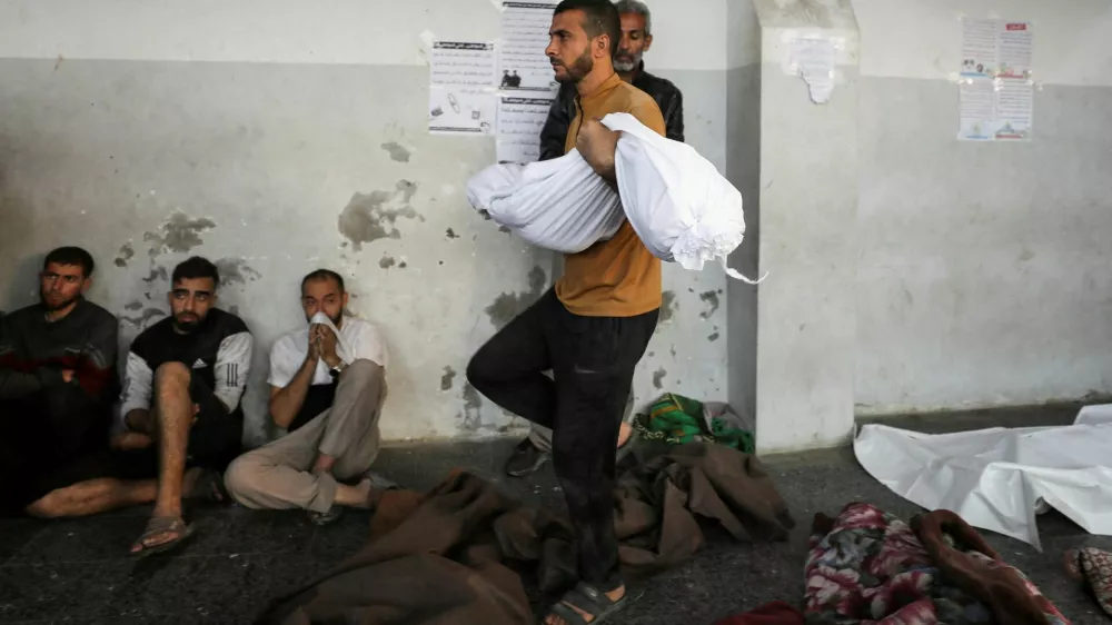 A man carries the dead body of a Palestinian killed in an Israeli strike on a house in Jabalia, at Al-Ahli hospital in Gaza City November 10, 2024. REUTERS/Dawoud Abu Alkas