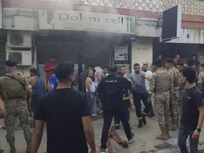 Lebanese soldiers and firefighters gather outside a mobile shop after what is believed to be the result of a walkie-talkie exploding inside it, in the southern port city of Sidon, Lebanon, Wednesday, Sept. 18, 2024. (AP Photo/Mohammed Zaatari)