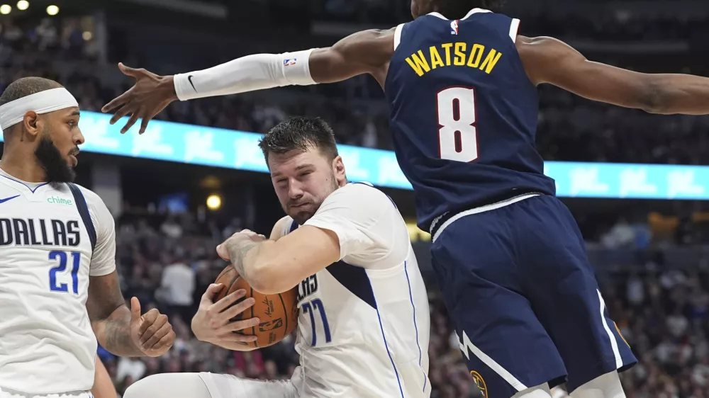 Dallas Mavericks guard Luka Doncic, center, pulls in a rebound as Denver Nuggets forward Peyton Watson defends in the second half of an NBA basketball game, Sunday, Nov. 10, 2024, in Denver. (AP Photo/David Zalubowski)