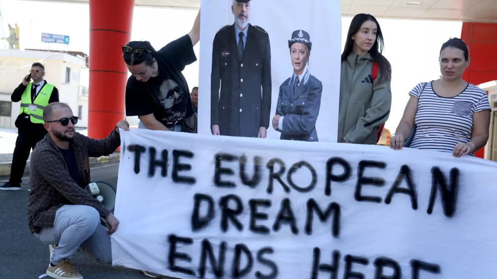 Activists holds a poster depicting Albanian Prime Minister Edi Rama and Italian Prime Minister Giorgia Meloni during a protest on the day migrants arrive on Italian navy ship Libra in Albania as part of a deal with Italy to process thousands of asylum-seekers caught near Italian waters, in Shengjin, Albania, October 16, 2024. REUTERS/Florion Goga