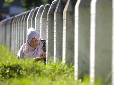 A Bosnian Muslim woman prays next to the grave of her relative, victim of the Srebrenica massacre, at the Srebrenica Memorial Centre in Potocari, Bosnia, Thursday, July 11, 2024. Thousands gather in the eastern Bosnian town of Srebrenica to commemorate the 29th anniversary of the Srebrenica massacre, Europe's only acknowledged genocide since the Holocaust. (AP Photo/Armin Durgut)