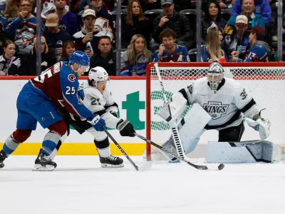 Nov 13, 2024; Denver, Colorado, USA; Los Angeles Kings defenseman Jordan Spence (21) clears the puck against Colorado Avalanche right wing Logan O'Connor (25) ahead of goaltender Darcy Kuemper (35) in the third period at Ball Arena. Mandatory Credit: Isaiah J. Downing-Imagn Images