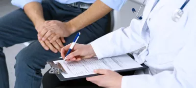 Female doctor holding application form while consulting man patient in hospital. Medicine and healthcare concept. / Foto: Andrei_r