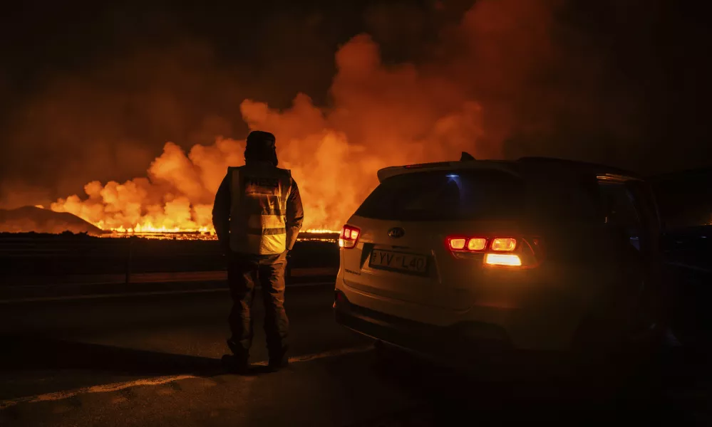 A press reporter watching a new volcanic eruption that started on the Reykjanes Peninsula the from Grindavikurvegur, the road to Grindavik in Iceland, Wednesday, Nov.20, 2024. (AP Photo/Marco di Marco)