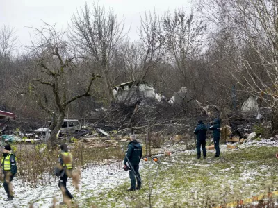 Lithuanian Emergency Ministry employees and police officers stand near the place where a DHL cargo plane crashed into a house near Vilnius, Lithuania, Monday, Nov. 25, 2024. (AP Photo/Mindaugas Kulbis)