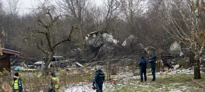 Lithuanian Emergency Ministry employees and police officers stand near the place where a DHL cargo plane crashed into a house near Vilnius, Lithuania, Monday, Nov. 25, 2024. (AP Photo/Mindaugas Kulbis)