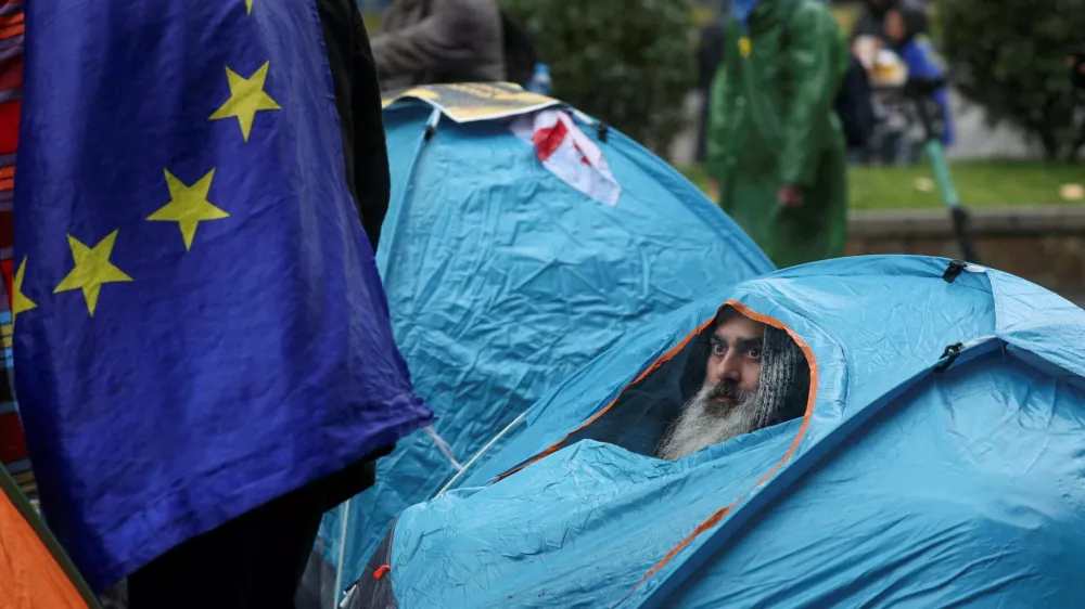 An opposition activist looks out of a tent during a rally to protest against the results of Georgia's parliamentary election, which the opposition say were rigged, as the new parliament holds the first session in Tbilisi, Georgia November 25, 2024. REUTERS/Irakli Gedenidze   TPX IMAGES OF THE DAY