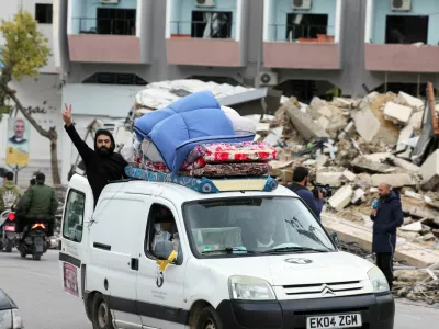 Moški pozdravlja iz natovorjenega avta na jugu Libanona, kjer se ljudje poskušajo vrniti na svoje domove. Foto: Reuters