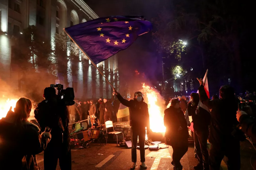 A supporter of Georgia's opposition holds a European Union flag while attending a rally to protest after the government halted the EU application process until 2028, by the Parliament building in Tbilisi, Georgia, November 29, 2024. REUTERS/Irakli Gedenidze