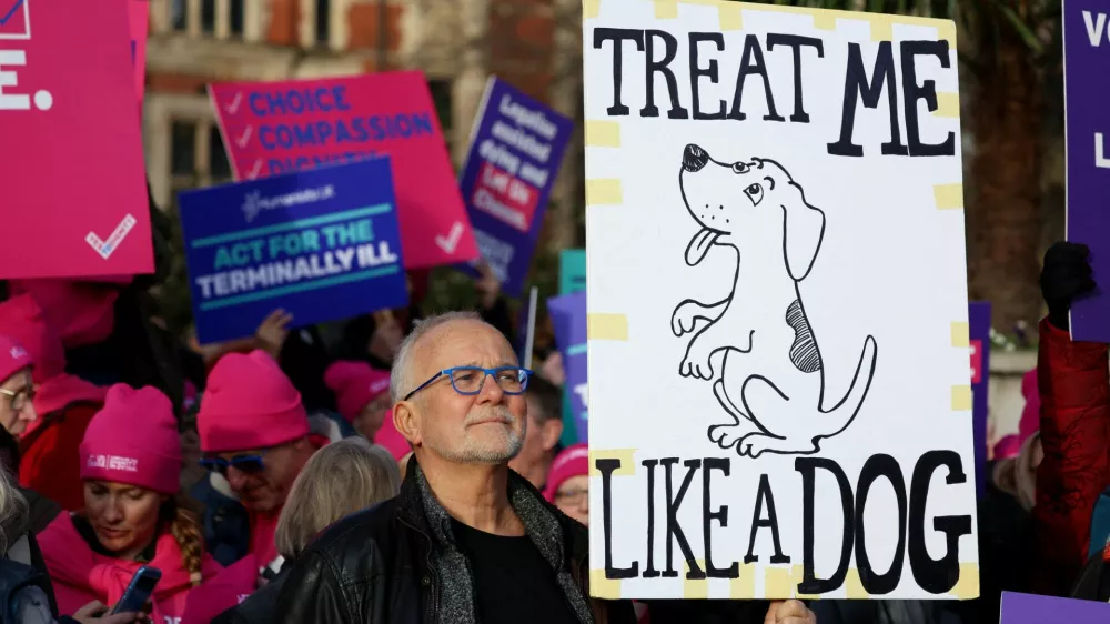 Graham Schafer holds a sign during a demonstration in support of assisted dying outside the British parliament as lawmakers debate the assisted dying law, in London, Britain, November 29, 2024. REUTERS/Mina Kim