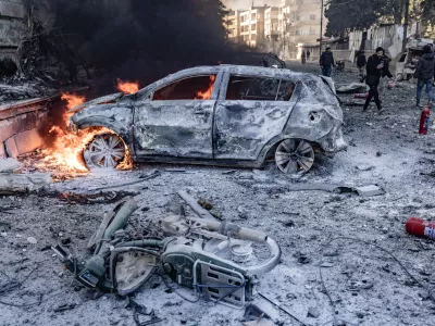 02 December 2024, Syria, Idlib: Vehicles burn while people inspect the damage caused by a Russian air strike on Idlib University. At least 11 people, including five children, were killed when Syrian and Russian warplanes launched a series of air strikes on rebel-held areas in north-western Syria on Monday, activists and a monitor group said. Photo: Anas Alkharboutli/dpa