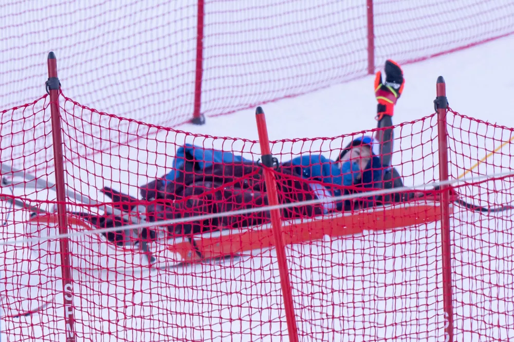 Nov 30, 2024; Killington, Vermont, USA; Mikaela Shiffrin of the United States waves to the crowd as she is taken off the course on a sled in the second run of the women's giant slalom at the Stifel Killington Cup alpine skiing race at Killington Resort. Mandatory Credit: Marc DesRosiers-Imagn Images