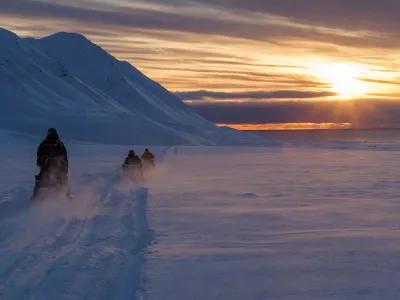 Scientists drive their snowmobiles cross the arctic towards Kongsfjord during sunset near Ny-Alesund, Svalbard, Norway, April 10, 2023. REUTERS/Lisi Niesner