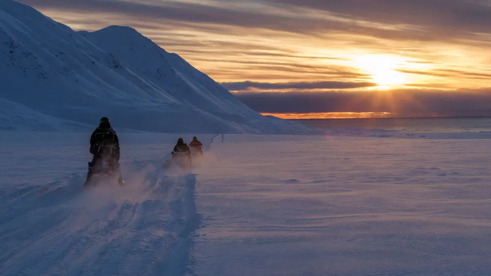 Scientists drive their snowmobiles cross the arctic towards Kongsfjord during sunset near Ny-Alesund, Svalbard, Norway, April 10, 2023. REUTERS/Lisi Niesner