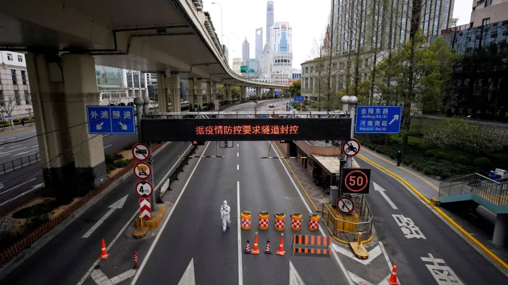 FILE PHOTO: A worker in a protective suit walks at an entrance to a tunnel leading to the Pudong area, after restrictions on highway traffic amid the lockdown to contain the spread of the coronavirus disease (COVID-19) in Shanghai, China March 28, 2022. REUTERS/Aly Song/File Photo