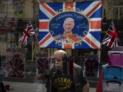 A man looks inside a souvenir shop decorated with a flag commemorating the coronation of King Charles III in central London, Wednesday, May 3, 2023. The Coronation of King Charles III will take place at Westminster Abbey on May 6. (AP Photo/Emilio Morenatti)