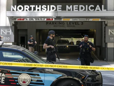 Law enforcement officers stand Northside Hospital Midtown medical office building, where five people were shot, Wednesday, May 3, 2023, in Atlanta. Authorities swarmed the city's bustling midtown neighborhood in search of the 24-year-old suspect. (Arvin Temkar/Atlanta Journal-Constitution via AP)