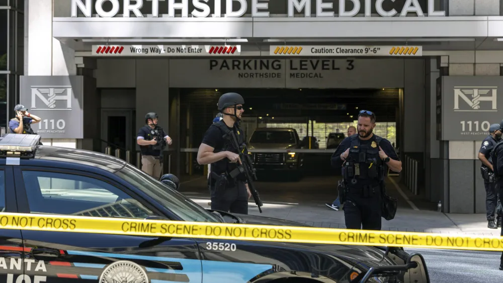 Law enforcement officers stand Northside Hospital Midtown medical office building, where five people were shot, Wednesday, May 3, 2023, in Atlanta. Authorities swarmed the city's bustling midtown neighborhood in search of the 24-year-old suspect. (Arvin Temkar/Atlanta Journal-Constitution via AP)