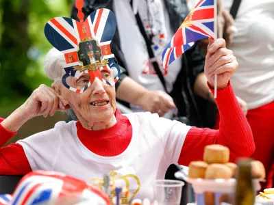 A woman waves a Union Jack flag as people celebrate Britain's King Charles' coronation with the Big Lunch at Regent's Park, in London, Britain, May 7, 2023. REUTERS/Piroschka Van De Wouw