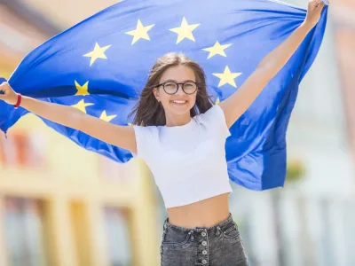 Cute happy young girl with the flag of the European Union in the streets somewhere in europe.