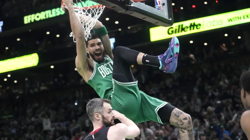 Boston Celtics forward Jayson Tatum, top, dunks as Miami Heat forward Kevin Love defends during the first half in Game 5 of the NBA basketball Eastern Conference finals series Thursday, May 25, 2023, in Boston. (AP Photo/Charles Krupa)